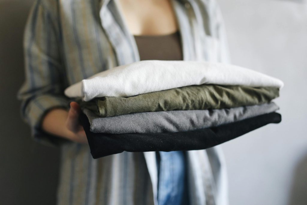 A close-up of a person holding neatly folded shirts, perfect for home organization themes.